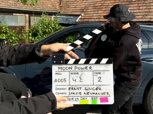 Filmklappe MOON vor Kameramann und E-Auto