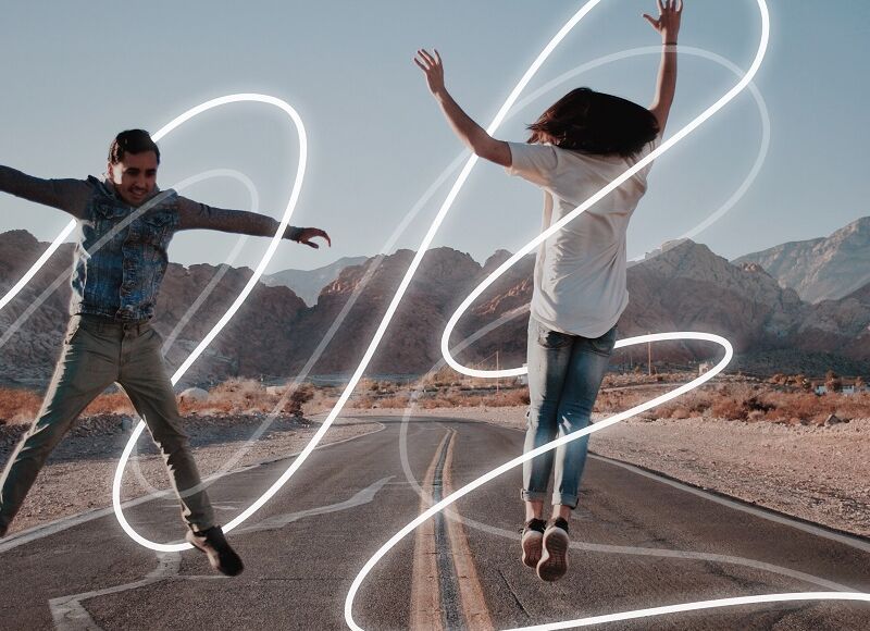 Two people dance on the street around the light lines of MOON