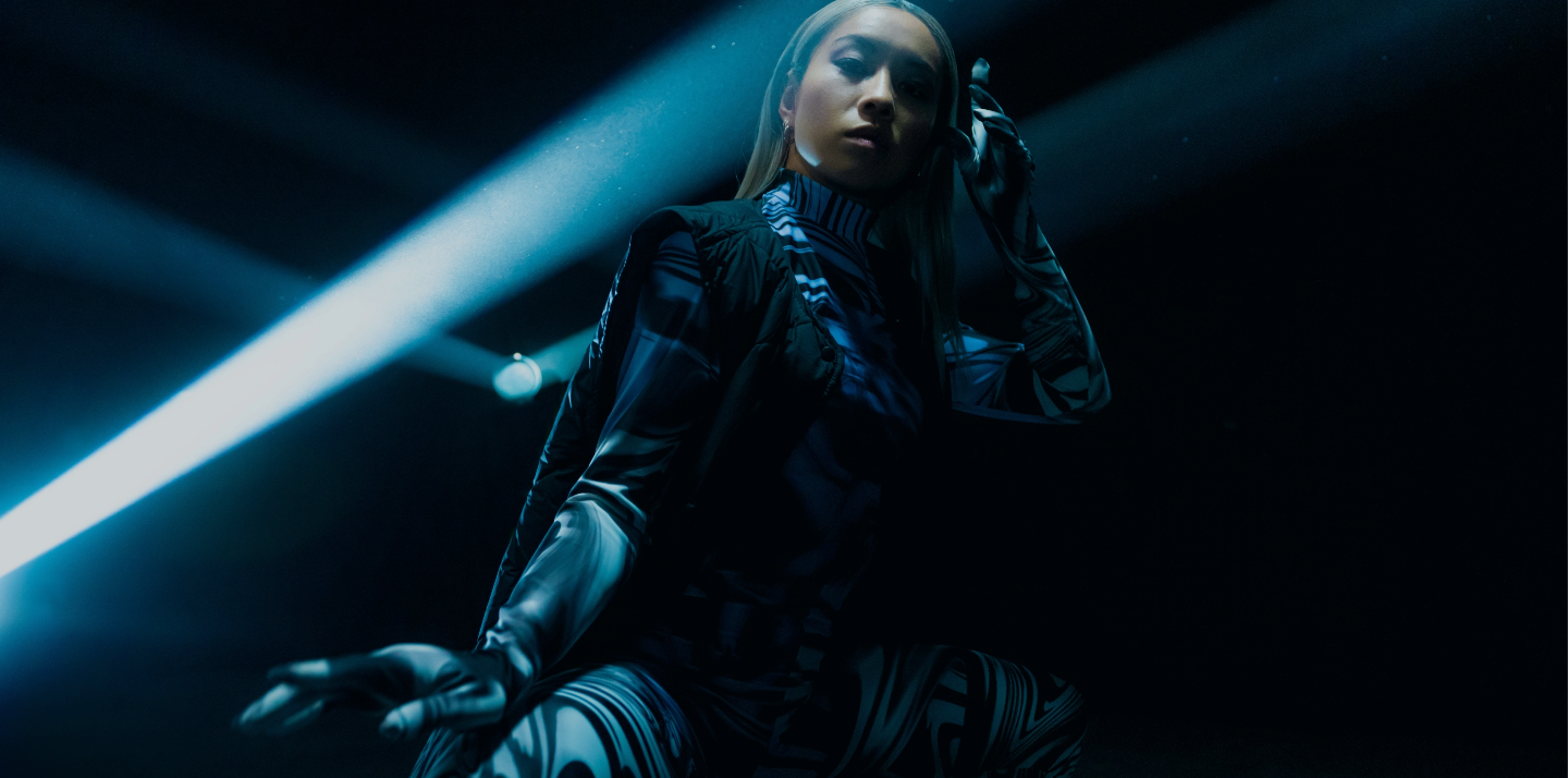 Asian woman in a clean dark space with light projectors surrounding her