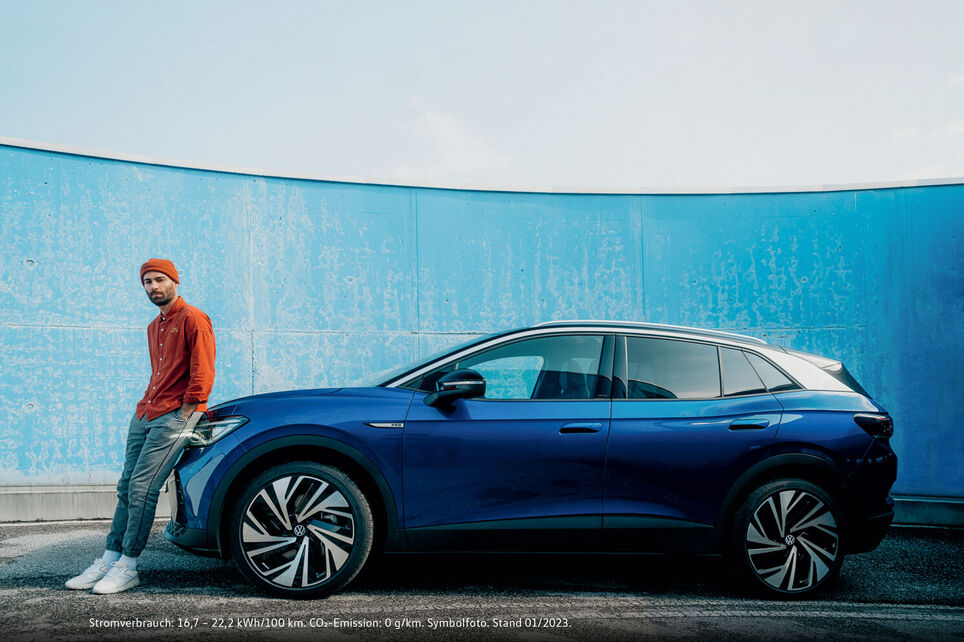 a young man sitting on a blue VW ID.4